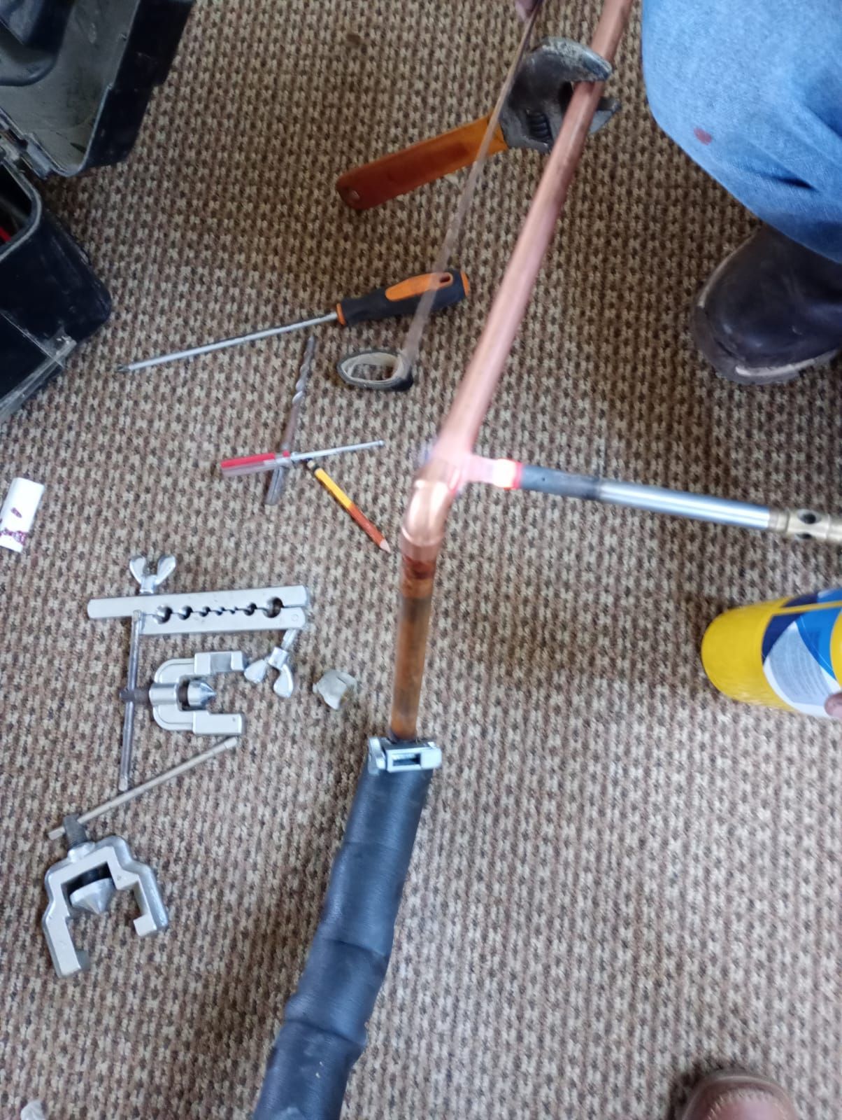 Primer plano de un cuadro de bicicleta rosa en reparación, con herramientas esparcidas sobre una alfombra.