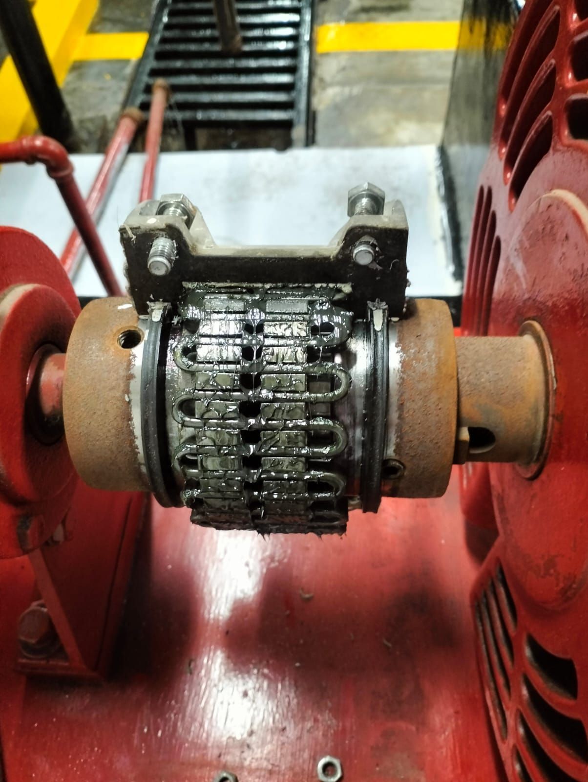 Primer plano de un componente de una máquina con un conjunto de cadena metálica montado sobre una base industrial roja.
