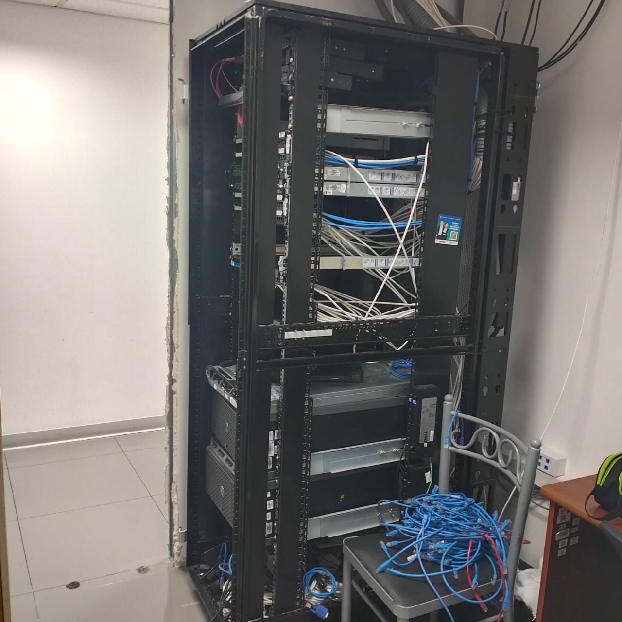 Rack de servidores con cables azules enredados en un cuarto de servicio.