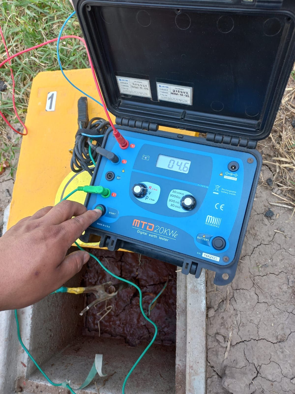 Mano sobre un dispositivo de prueba azul con cables en el exterior