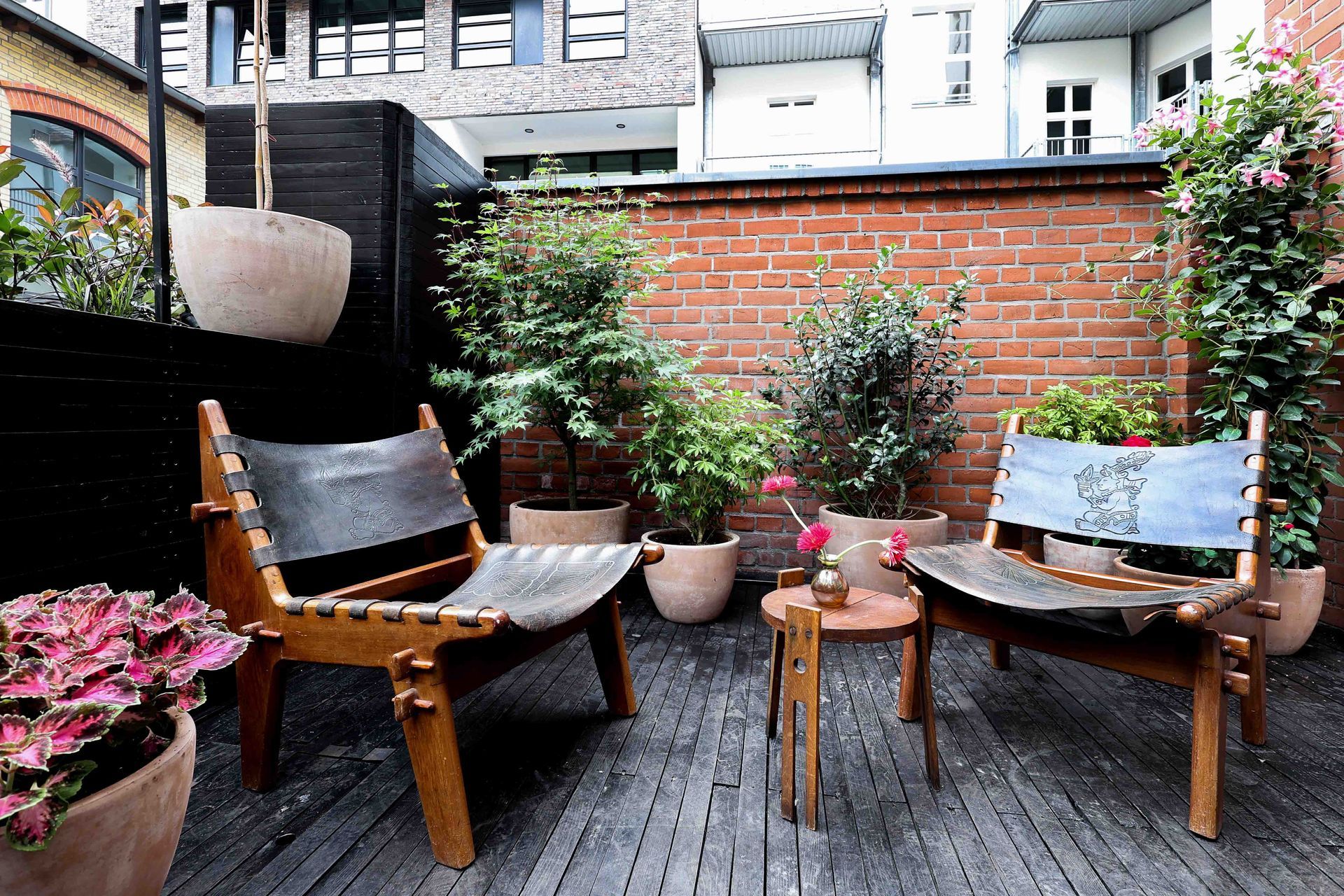 Terrasse mit Holzsesseln und Pflanzen im Hof