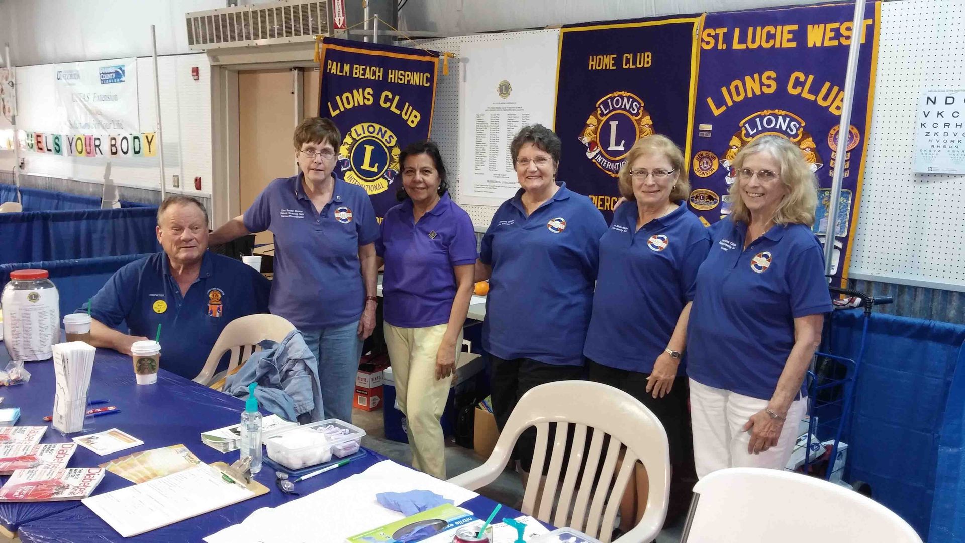 A group of people are posing for a picture in front of a lion club banner.