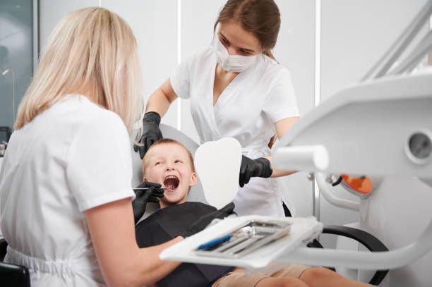 At Rabel Family Dental in Baton Rouge, LA, two female dentists perform a pediatric dentistry examination on a boy‘s teeth.