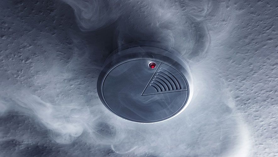 Un detector de humo en el techo del que sale humo.