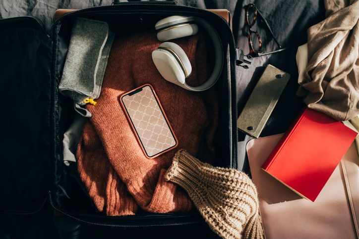 Suitcase filled with sweaters, headphones, and books, ready for a long-term stay at The Saddlery® Madison