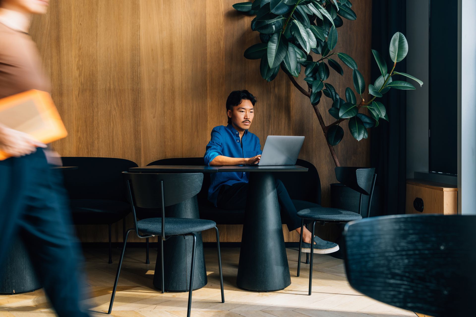 Person working remotely on a laptop in a modern coffee shop workspace