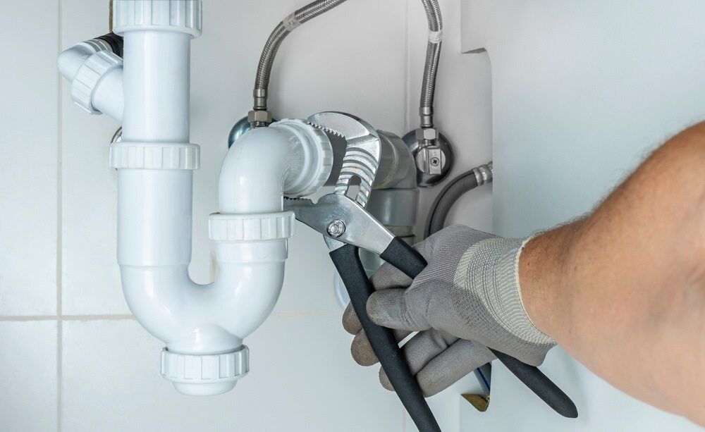 A Plumber Is Fixing A Sink Pipe With A Wrench — Malouf Plumbing In Mary Valley, QLD