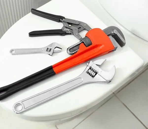 A Toilet With A Wrench And Pliers On It — Malouf Plumbing In Pie Creek, QLD