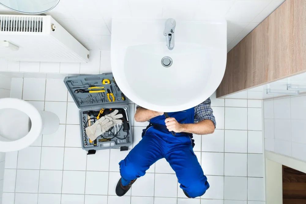 A Plumber Is Fixing A Sink In A Bathroom — Malouf Plumbing In Pie Creek, QLD