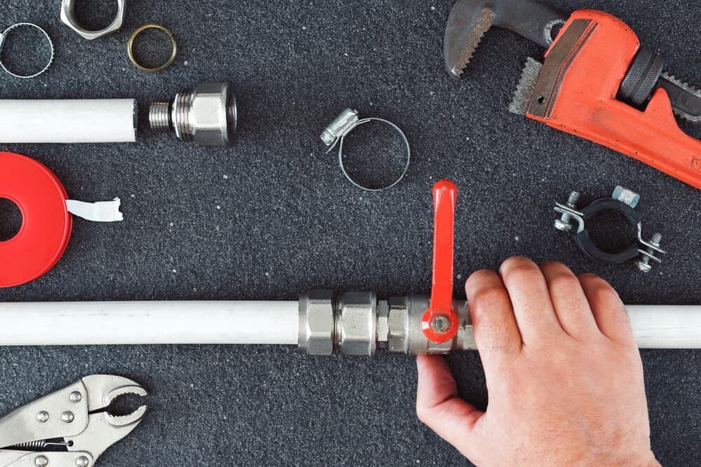 A Person Is Fixing A Pipe With A Wrench — Malouf Plumbing In Rainbow Beach, QLD