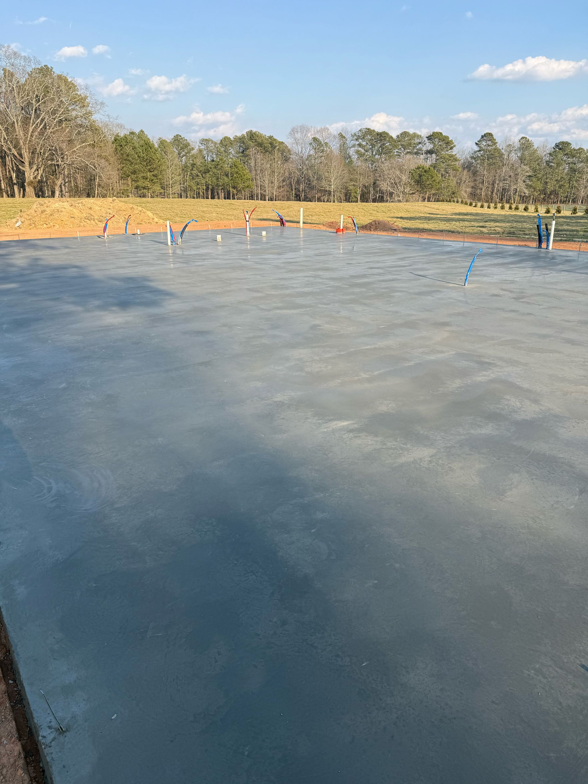 Frozen pond in a wooded park with a few people standing on the ice under a clear blue sky