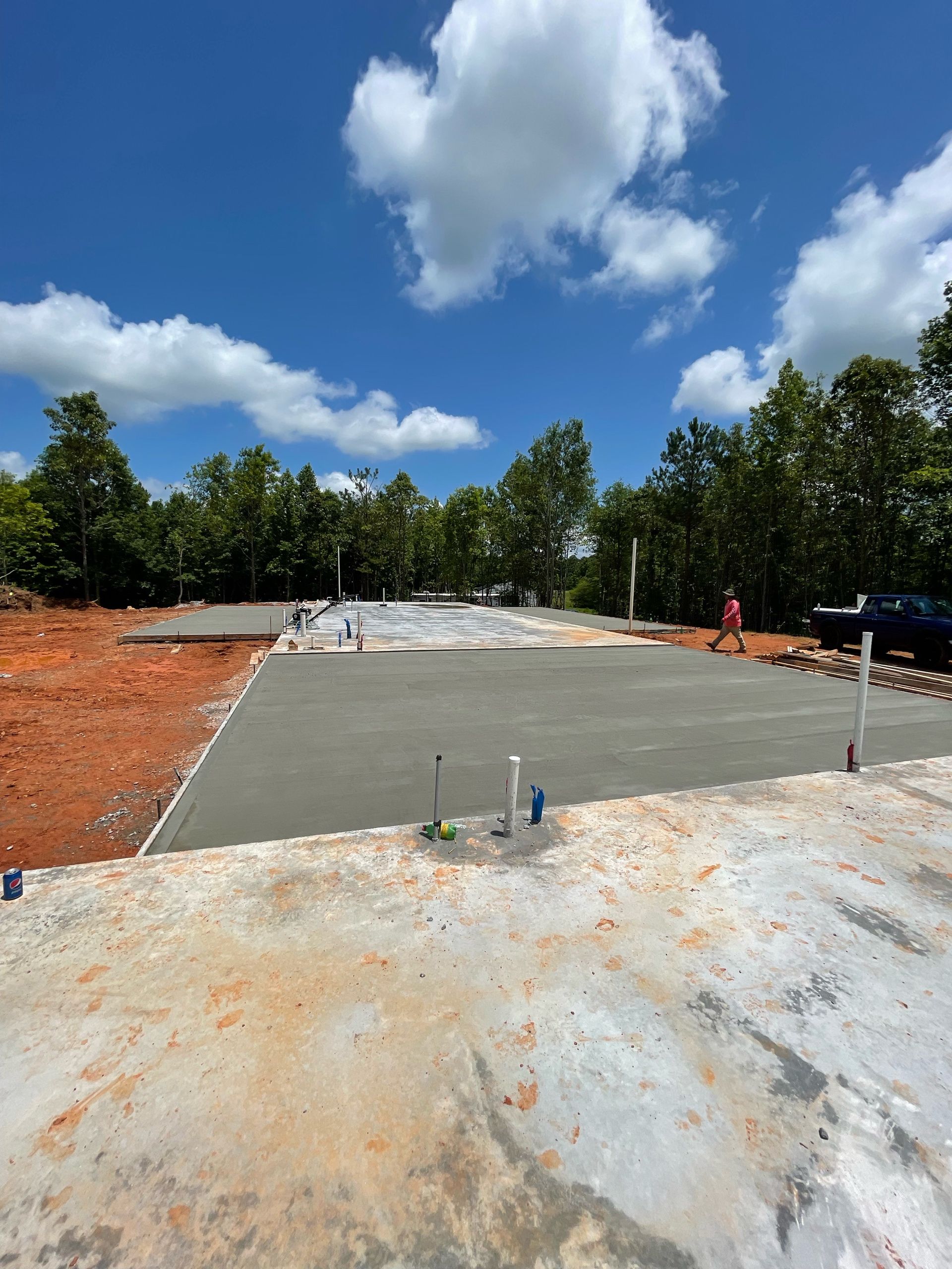 Concrete foundation under construction on a sunny site with trees and blue sky