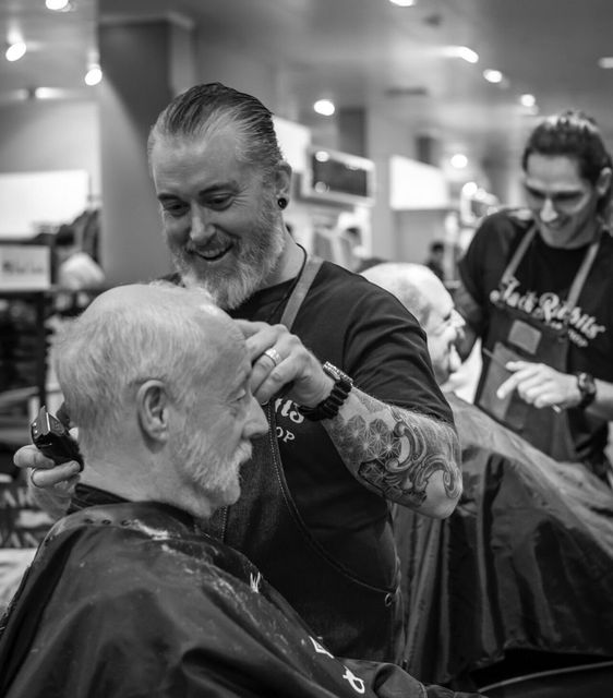 A black and white photo of a man getting his hair cut