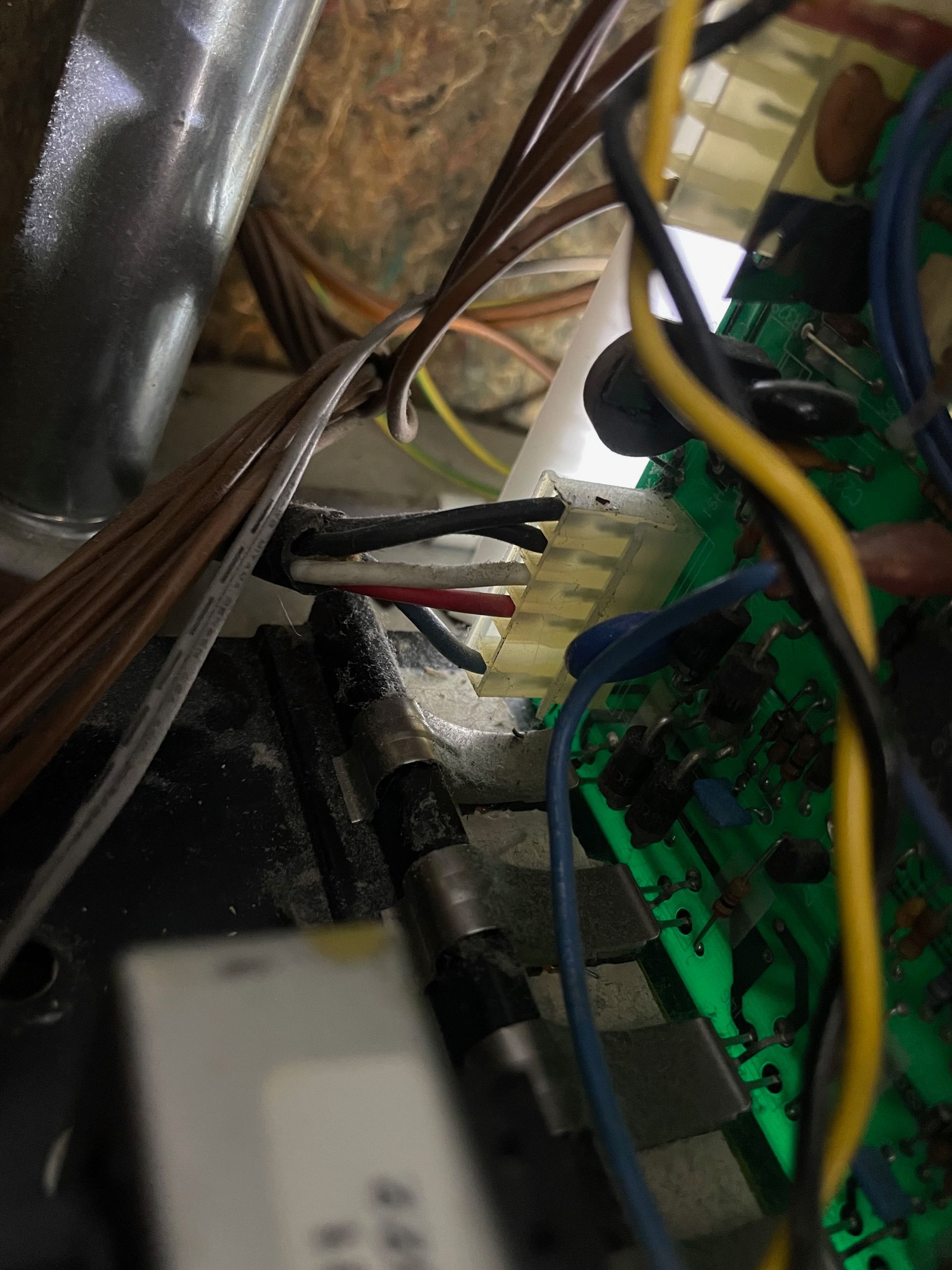 Close-up of electrical wiring connected to a circuit board. Wires are various colors, including white, black, red, and yellow.