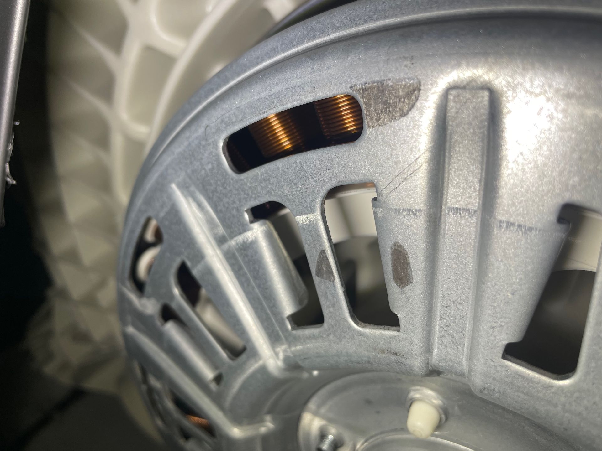 Close-up of a silver electric motor, showing copper coils and ventilation slots.