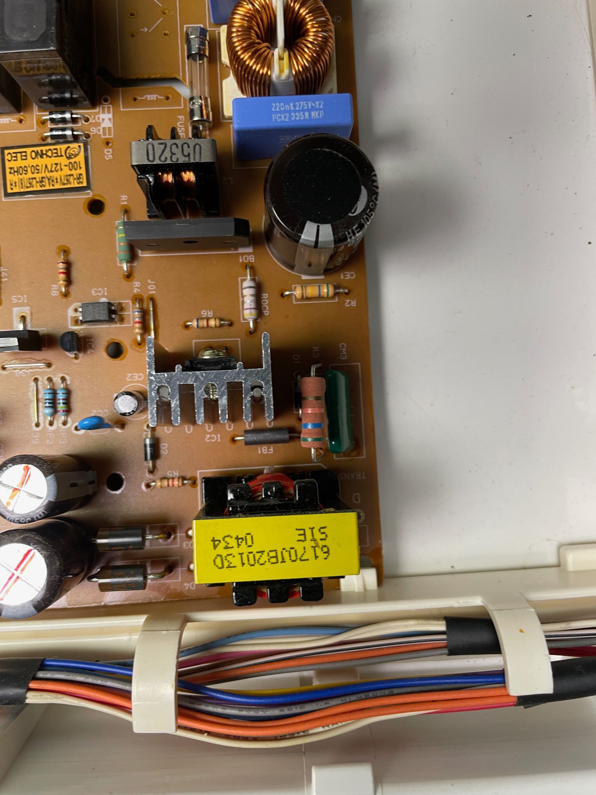 A close-up of a circuit board with various electronic components. Wires are bundled and secured below the board.
