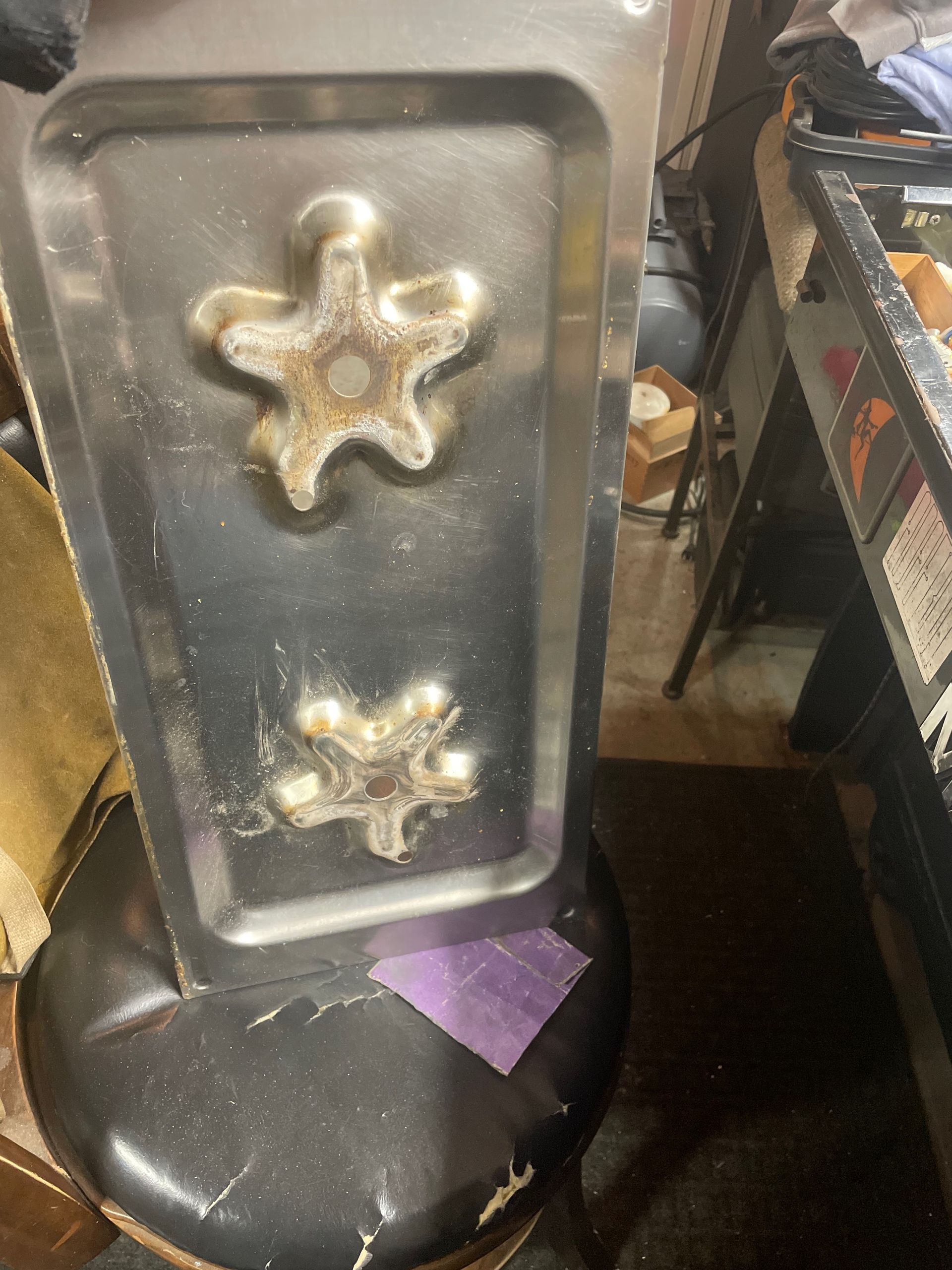 Stainless steel tray with two starfish-shaped indentations, resting on a black stool.