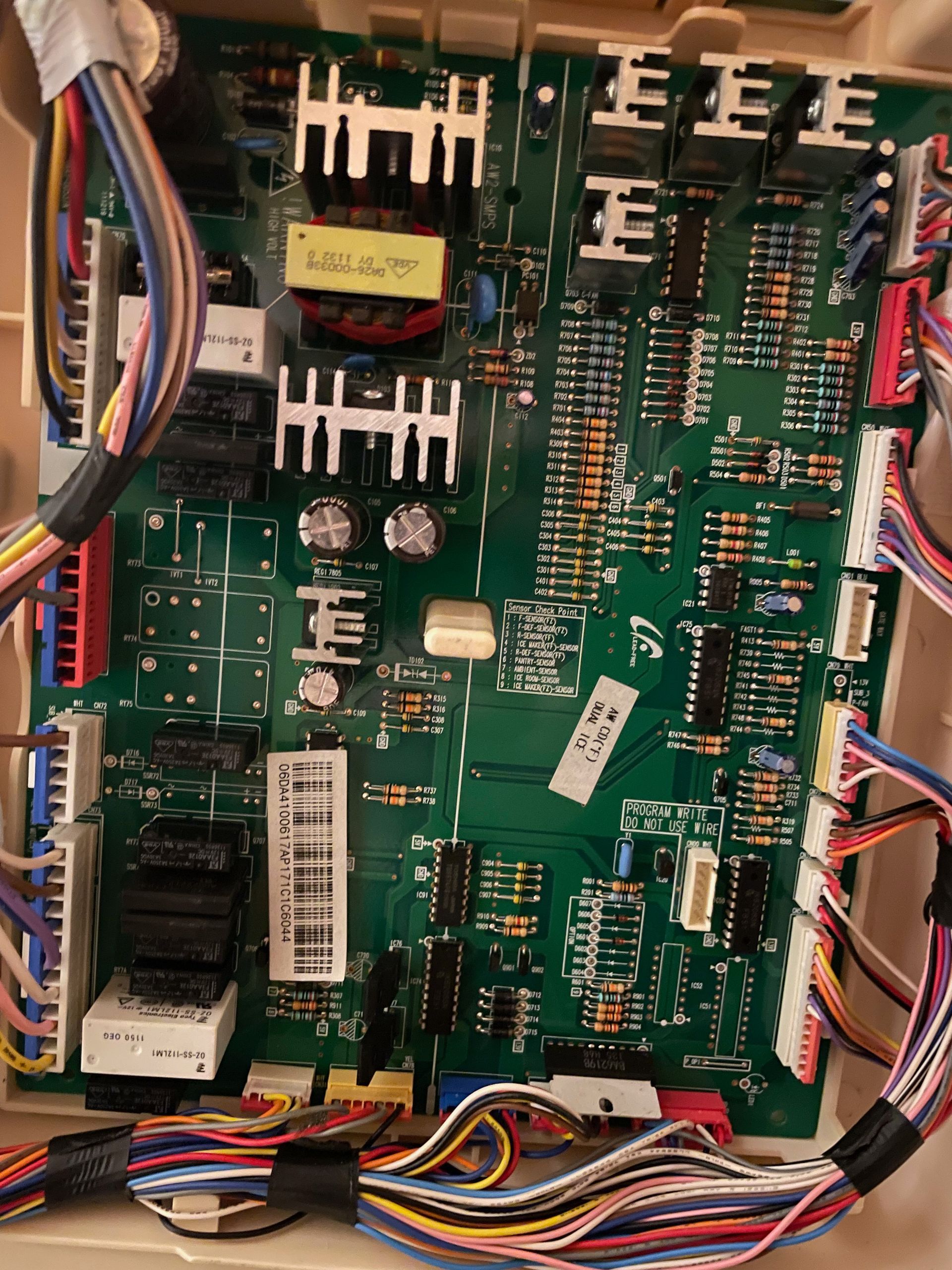 A green circuit board with various electronic components, wires, and connectors, housed in a beige enclosure.