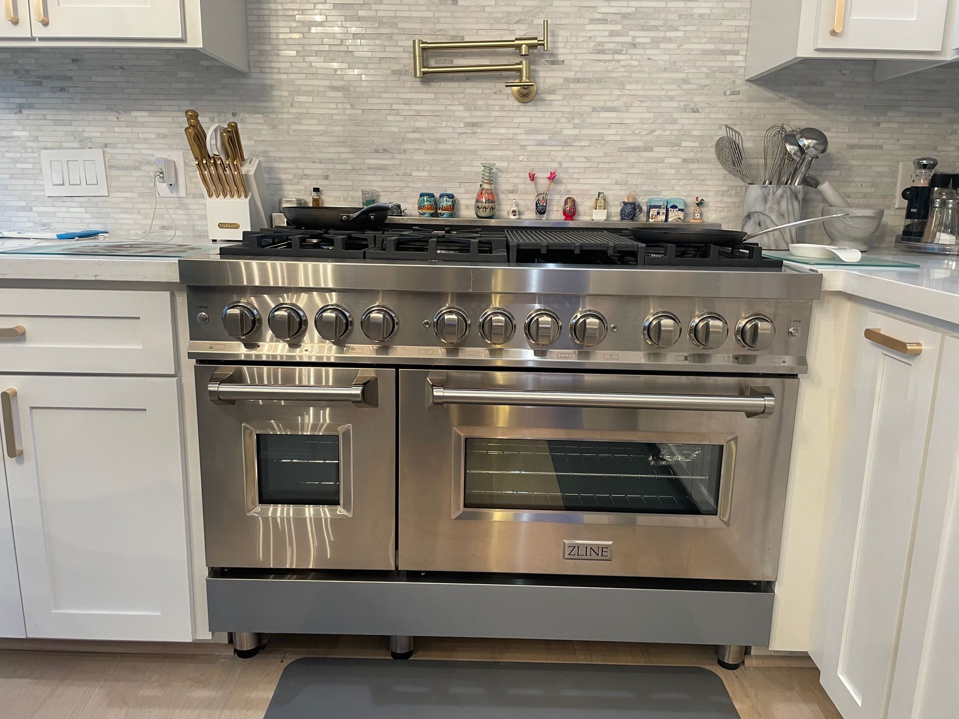 Stainless steel Viking range in a modern white kitchen with a backsplash and pot filler.