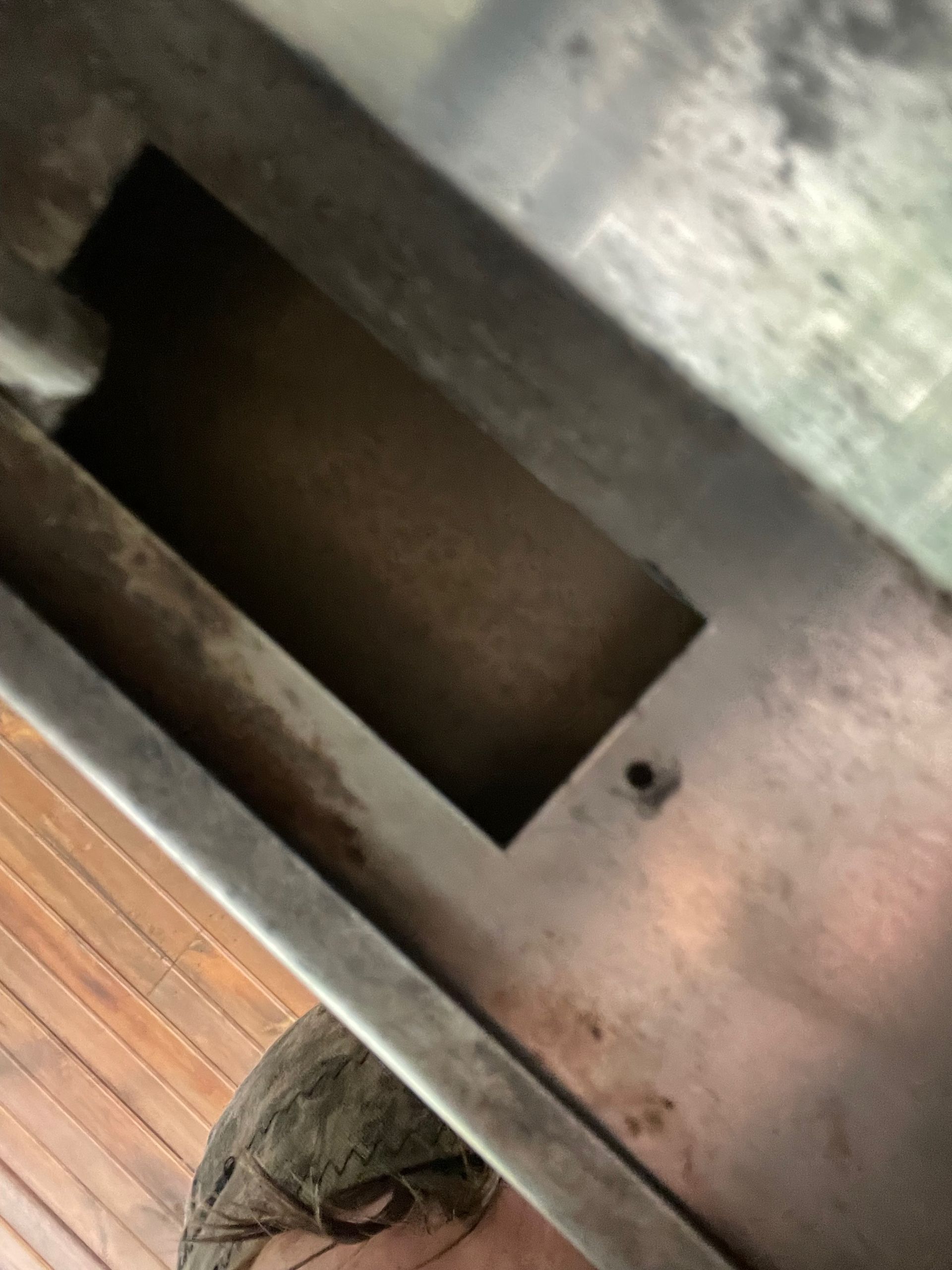 A close-up view shows a rectangular opening in a metal surface, with a small hole visible.