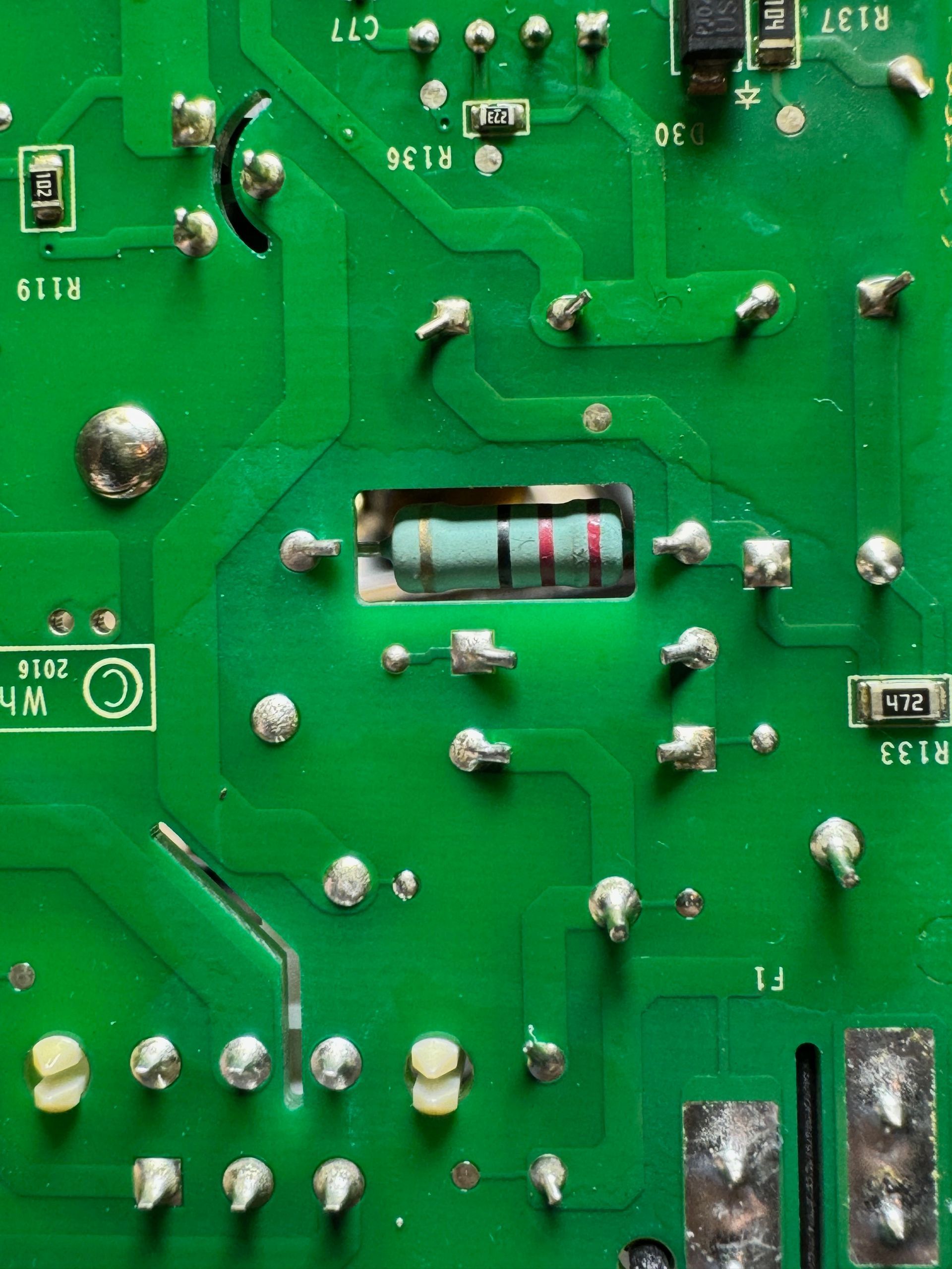 Green circuit board with several soldered components, including a rectangular resistor and various solder points.