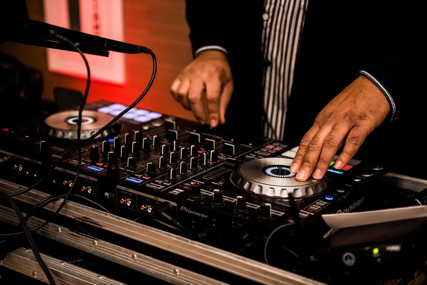 A dj is playing music on a mixer at a party.