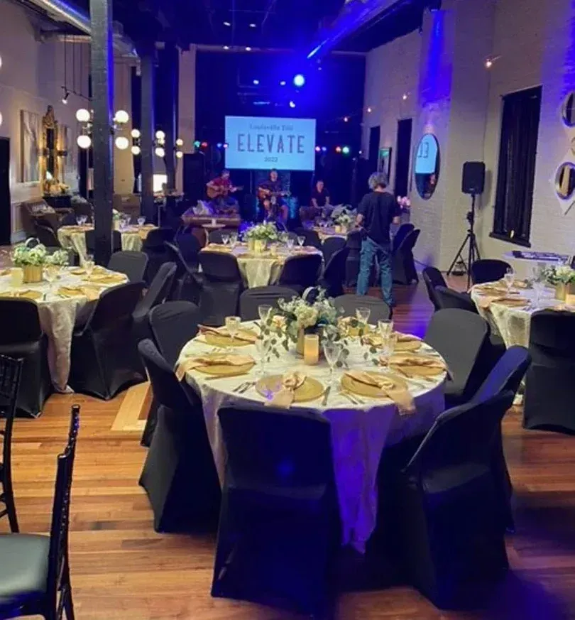 A large room filled with tables and chairs and a screen that says elevate