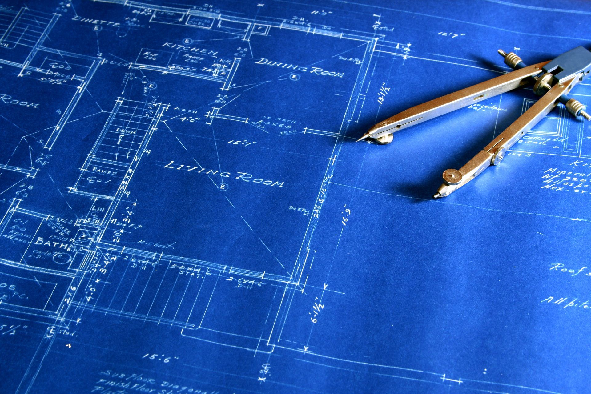 A pair of compasses laying on top of a blueprint