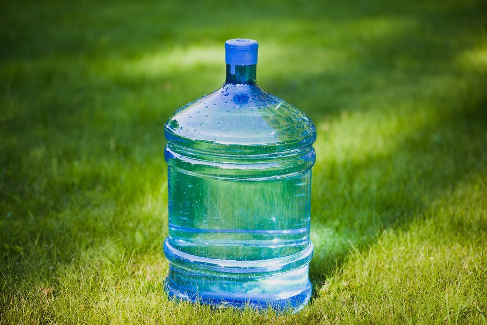 Large Blue Water Jug Standing on Green Grass Outdoors — Ts Jeffree Contractors in Mount Isa, QLD