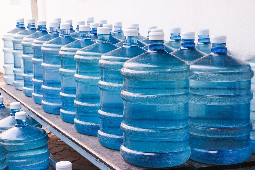 Rows of Large Blue Water Jugs Lined Up on a Conveyor in a Bottling Facility — Ts Jeffree Contractors in Burketown, QLD