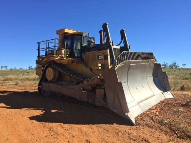 Yellow Caterpillar bulldozer on red dirt, under a blue sky.— Ts Jeffree Contractors in Cloncurry, QLD
