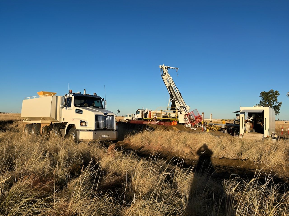 A drilling rig and support trucks in a field under a clear blue sky.— Ts Jeffree Contractors in Burketown, QLD