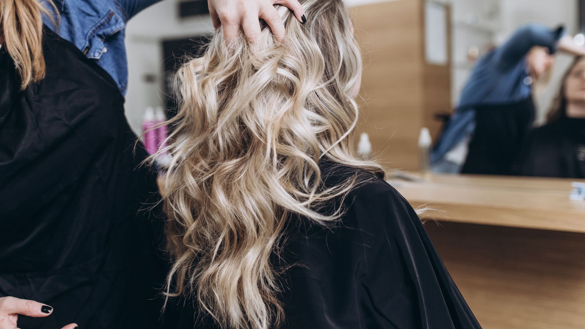 A woman is getting her hair done by a hairdresser in a salon.