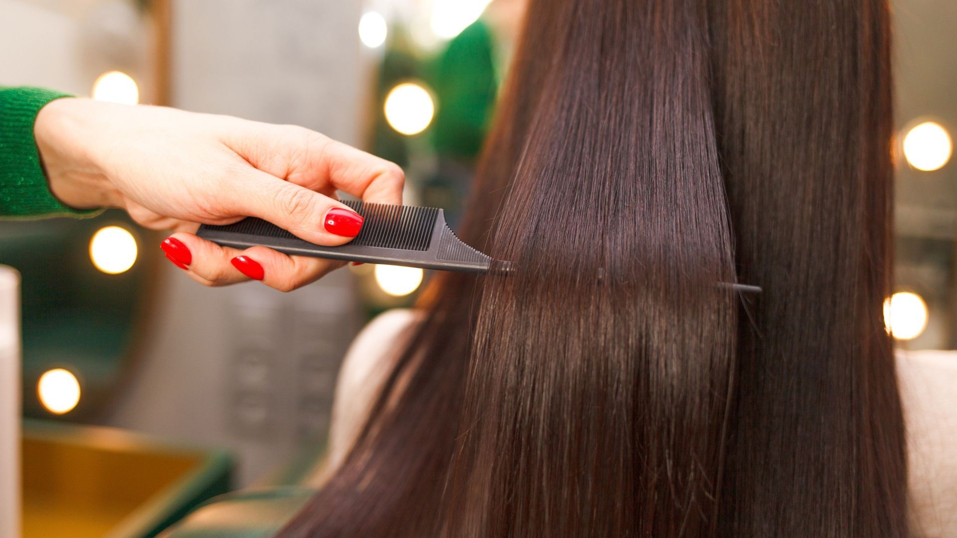 A woman is getting her hair combed by a hairdresser in a salon.