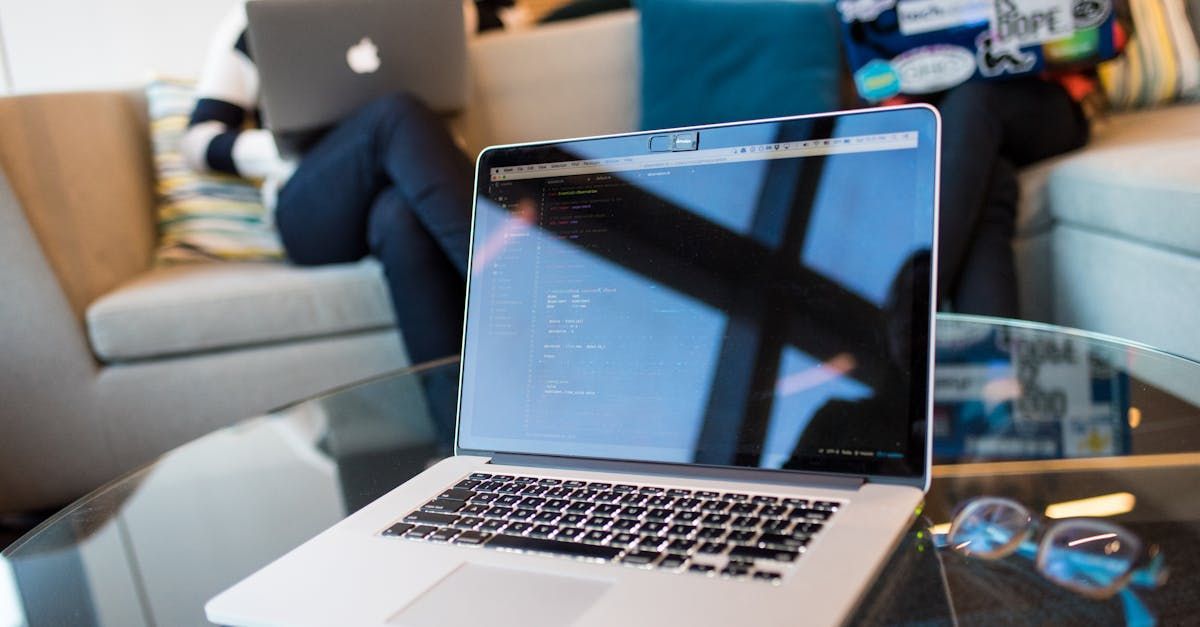 A person is sitting on a couch using a laptop computer.