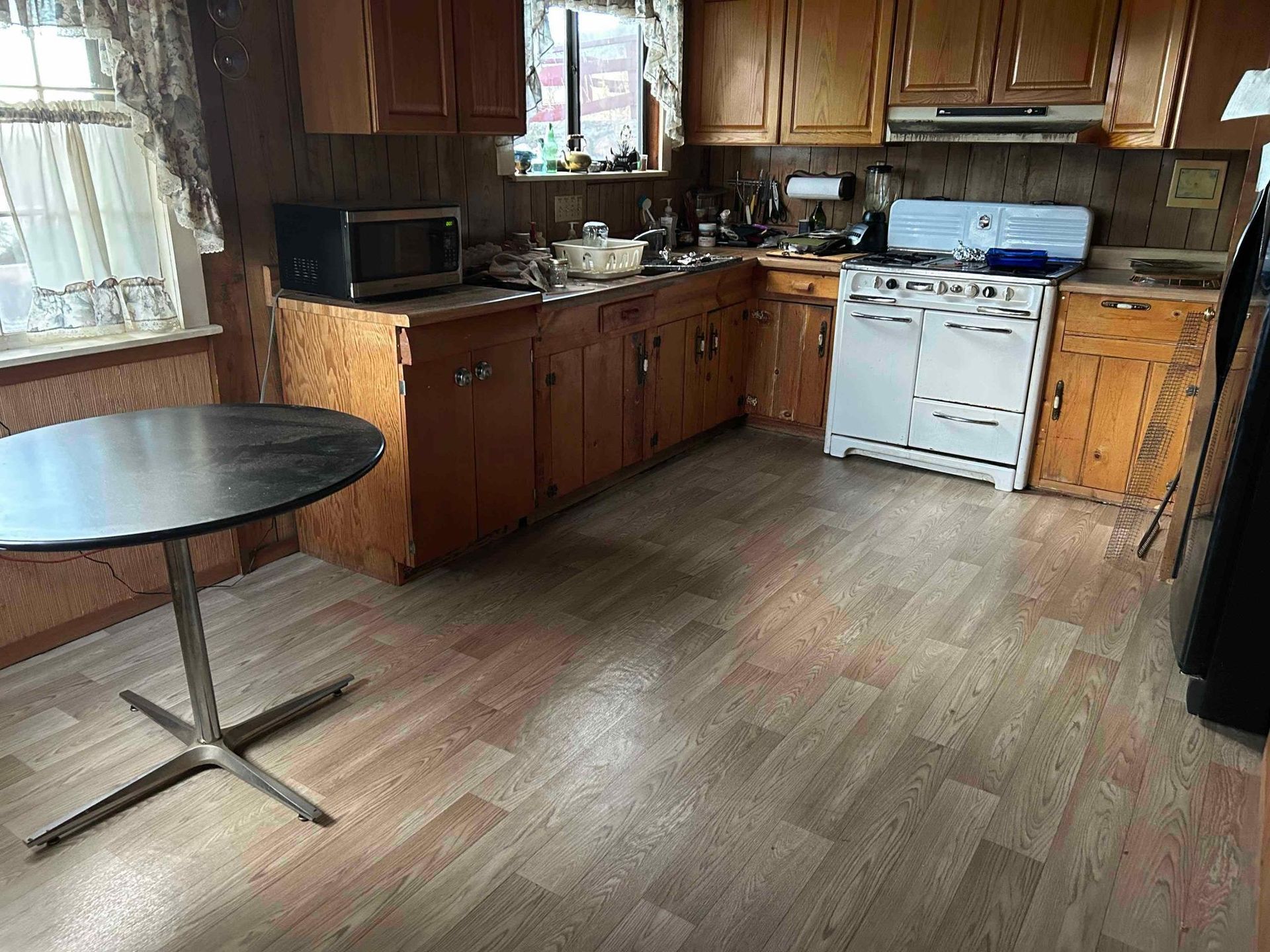 Kitchen with wooden cabinets, a white stove, a round table, and a window.