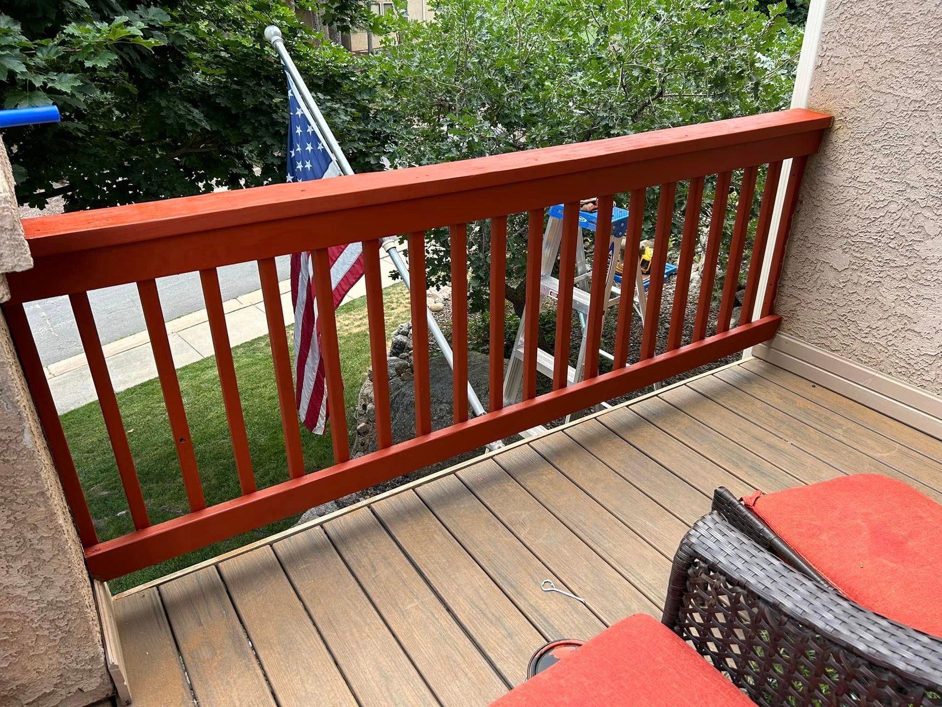 Orange painted railing on a deck overlooking grass, American flag visible.