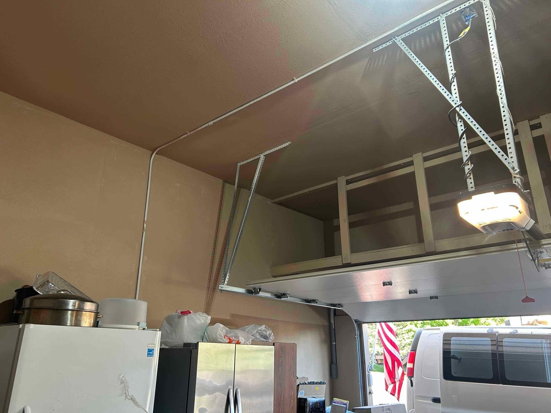 Garage storage unit installed near the ceiling, above a parked vehicle.