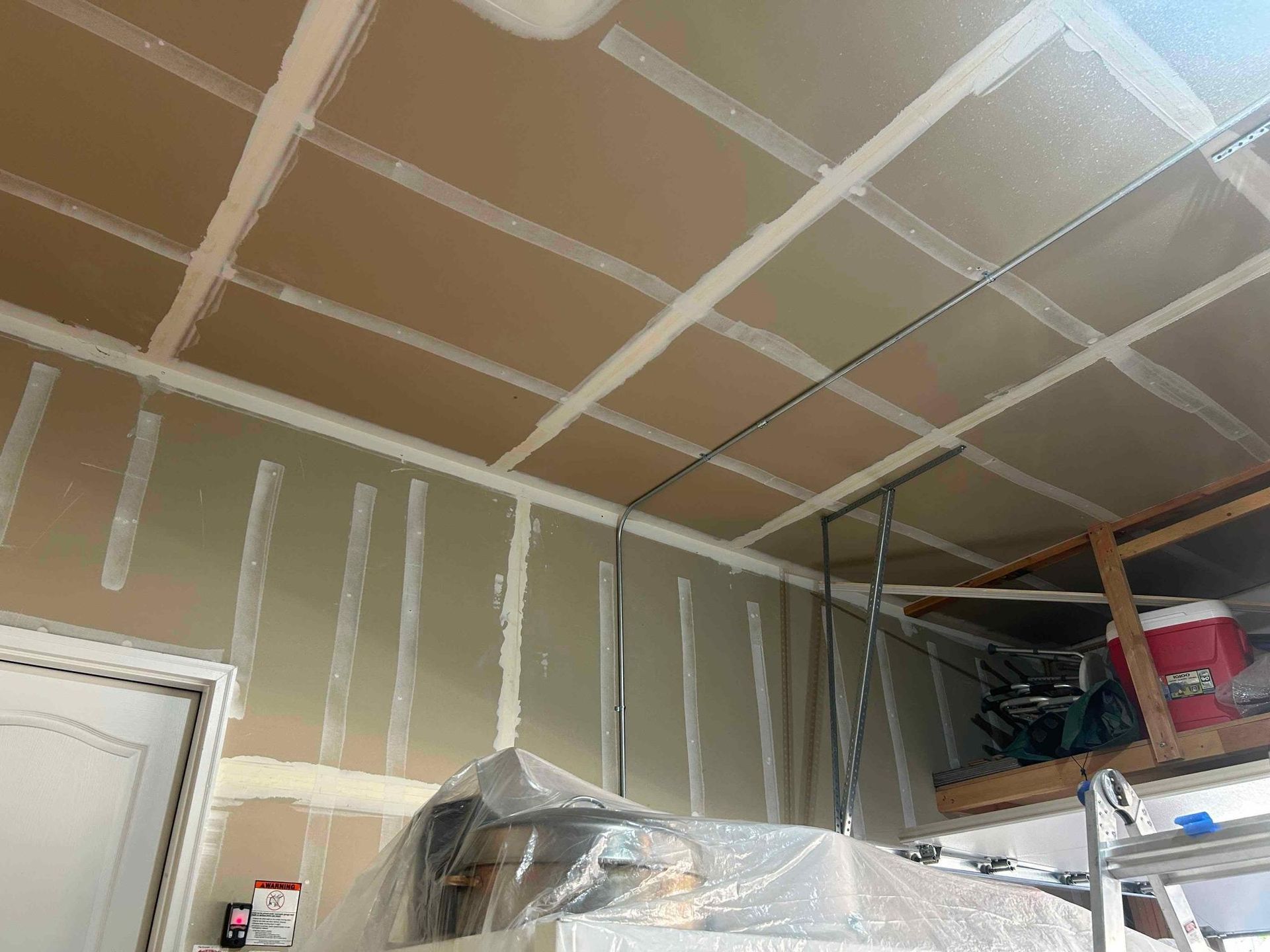 Garage ceiling and wall construction with drywall and unfinished tape.