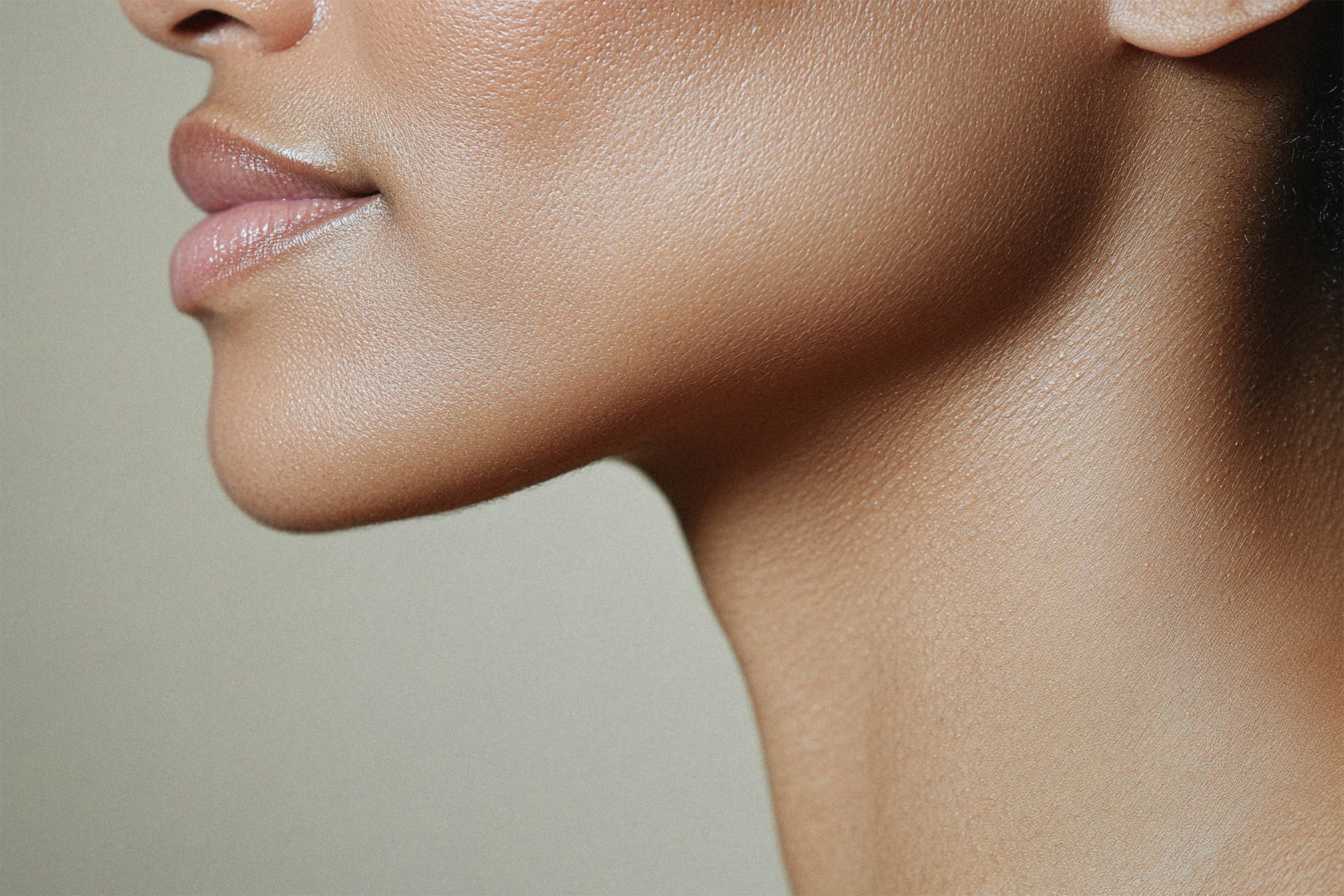Close-up of a person's face and neck, with dewy skin, soft lighting.