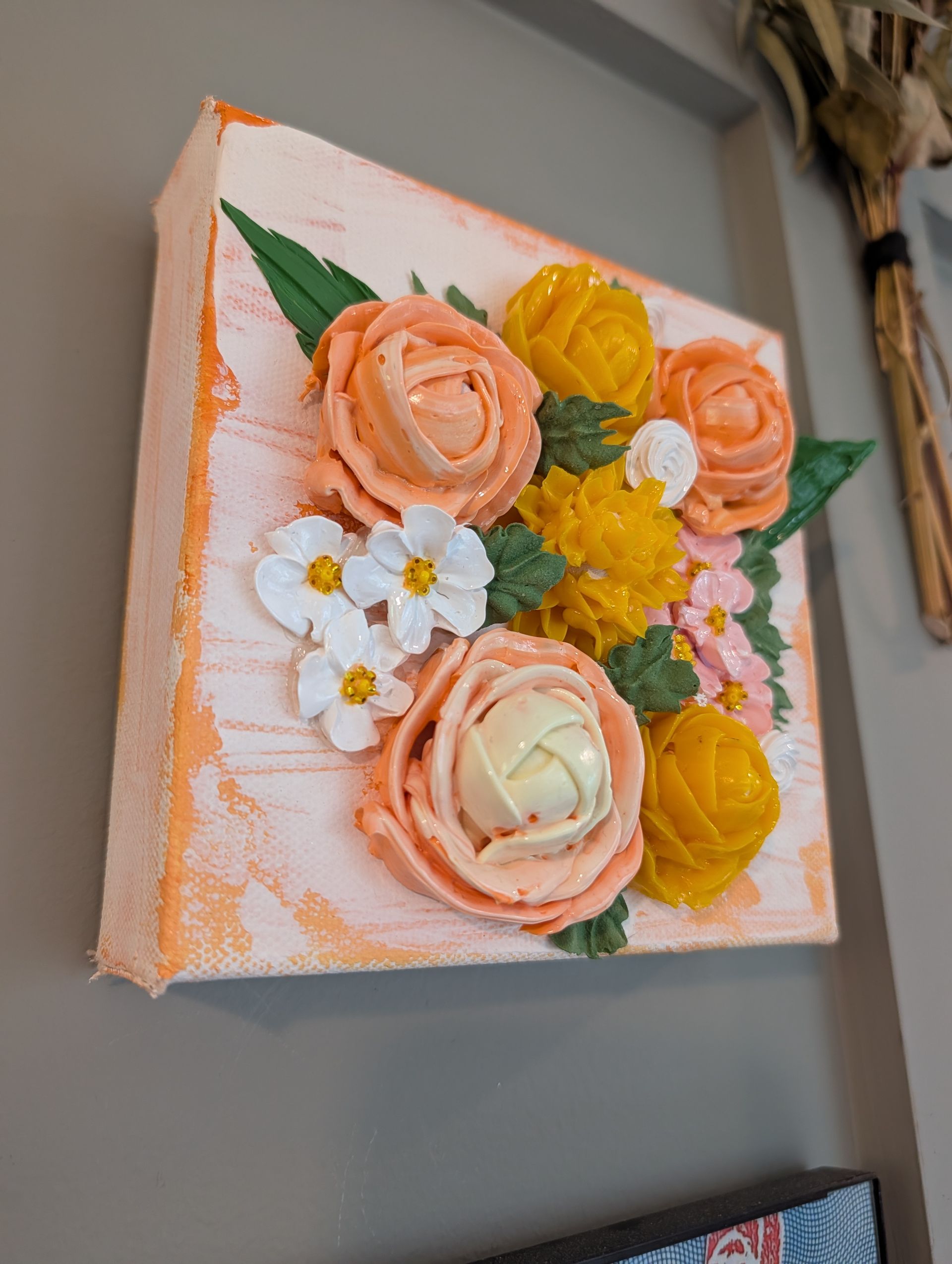 Floral canvas wall art with peach, yellow, and white flowers and green leaves on a gray wall
