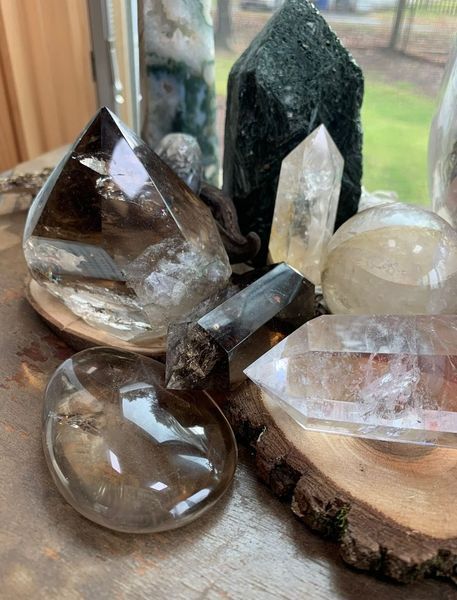 Crystals of various shapes and colors rest on wood slices. A window is in the background.