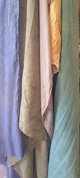 Several fabric rolls in varying pastel colors hang close together.