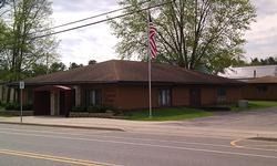 Brick office building with a U.S. flag by the roadside, surrounded by trees