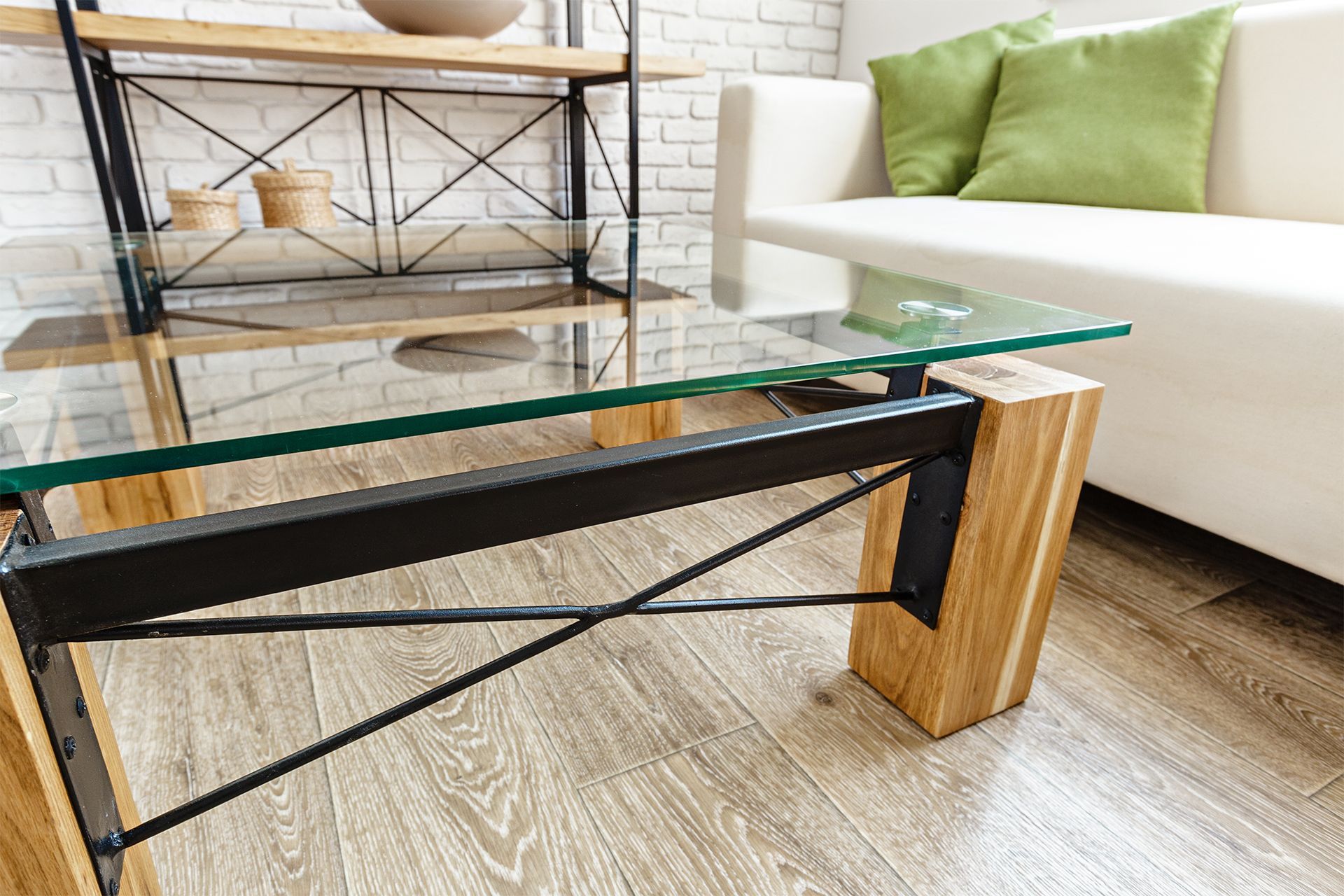 Modern glass coffee table with black metal frame and wood legs in a bright living room.