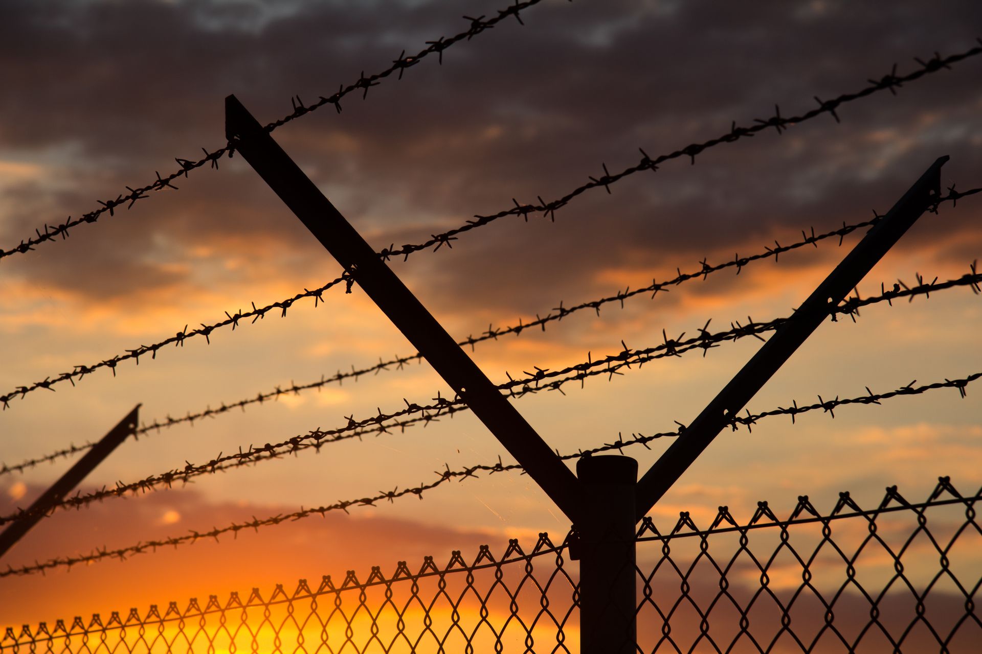 A barbed wire fence with a sunset in the background