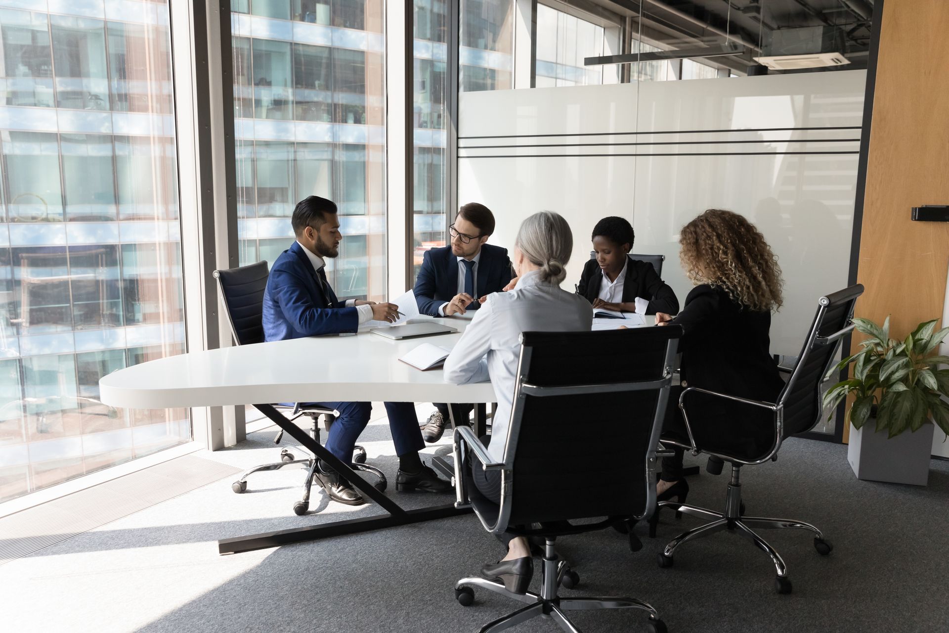 A group of people are sitting around a table in a conference room having a meeting.