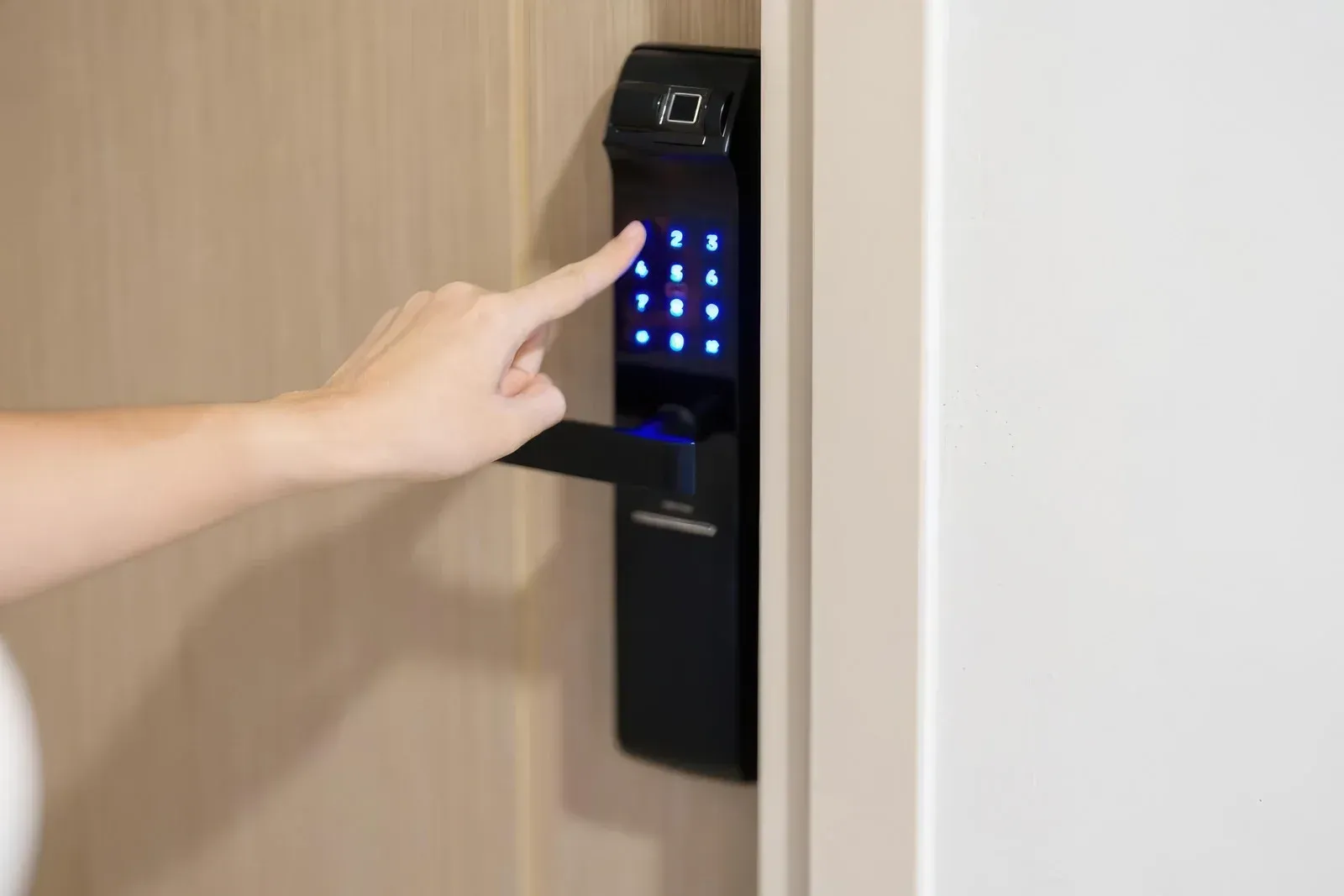 Hand pressing a blue-lit keypad on a black door lock