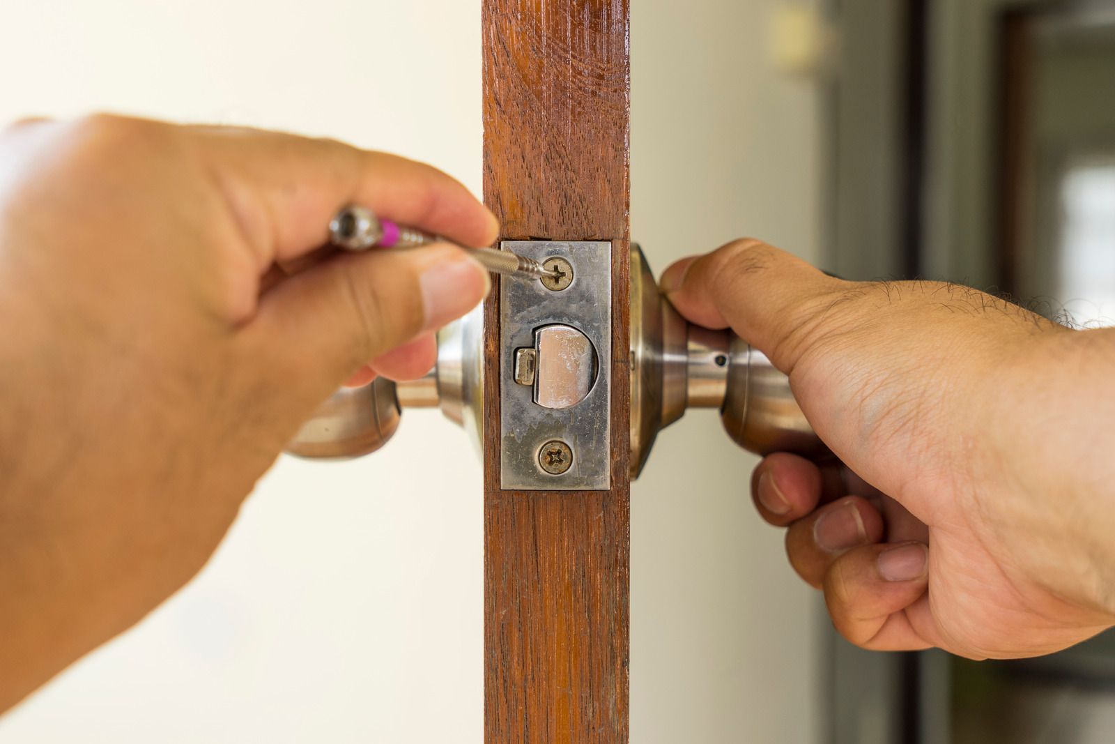 A man is fixing a door with a screwdriver.