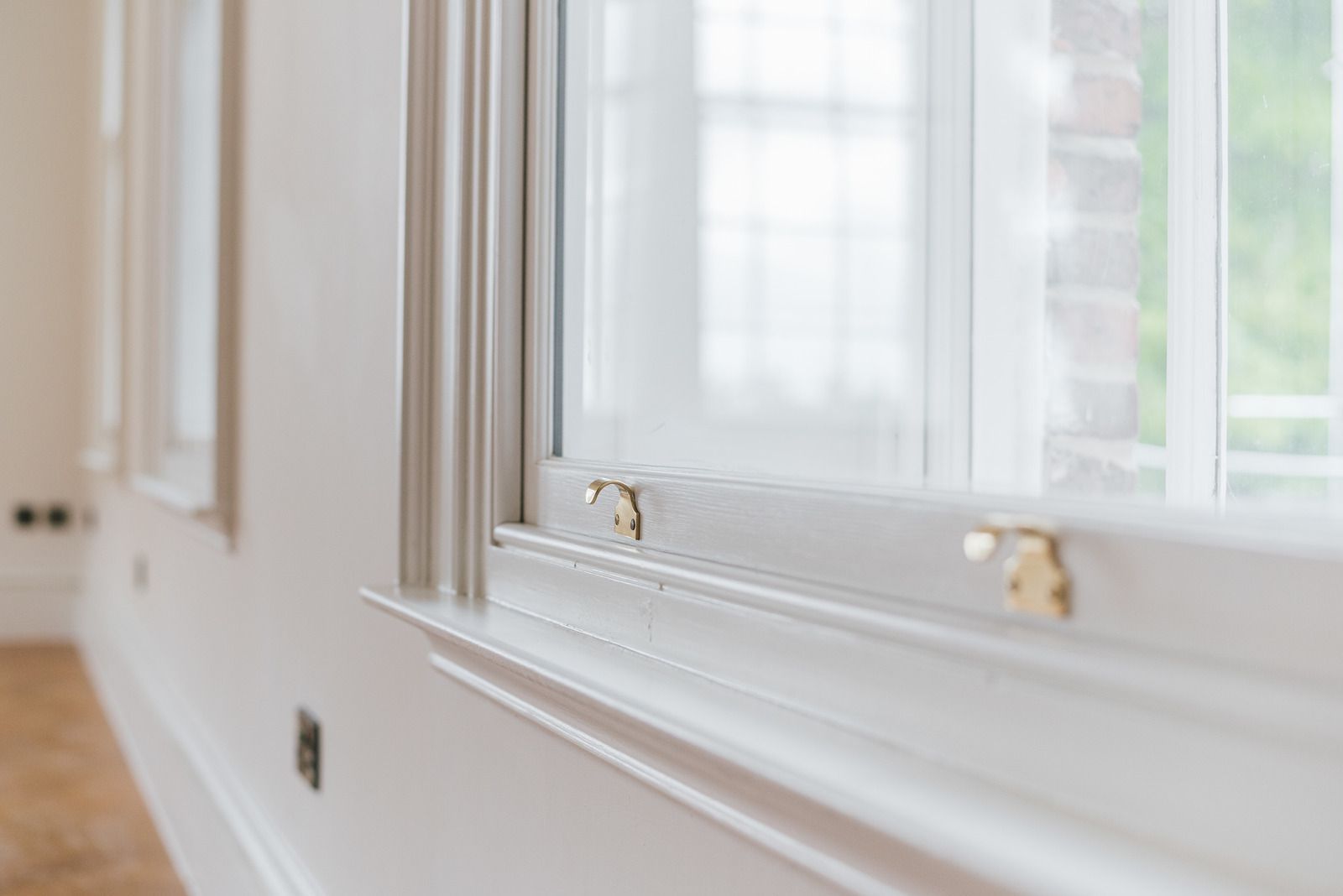 Bright white interior window with molding and brass latches in a softly lit room